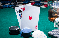 Sobre una mesa hay dos cartas y varios montones de fichas de casino.
