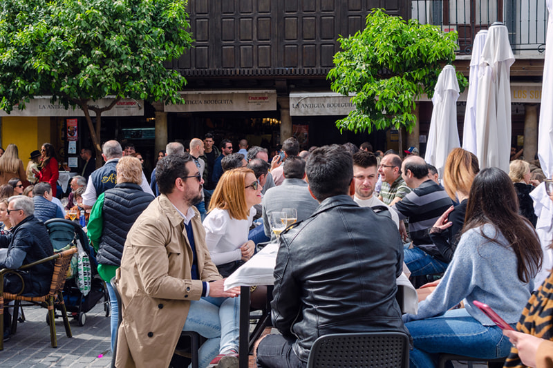 Grupo de personas reunidas en una terraza de Sevilla durante el tardeo, disfrutando del buen tiempo y de la vida social.