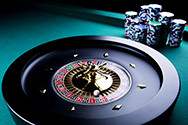 Una ruleta y varias pilas de fichas en una mesa de casino.