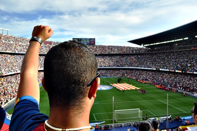 Un aficionado anima a su equipo en un campo de fútbol.