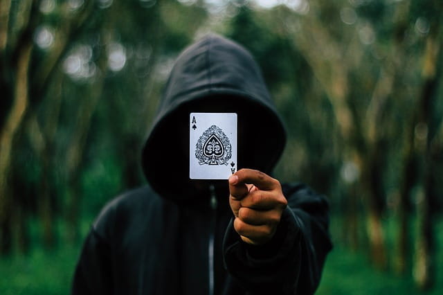 Jugador de póker con sudadera mostrando un as de picas.