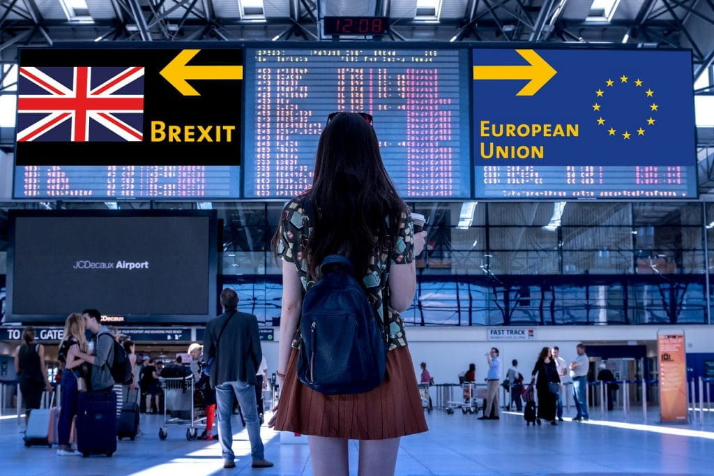 Mujer de espaldas frente a dos carteles mostrando la bandera del Reino Unido y otra de la Unión Europea.