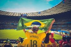 Un aficionado levanta la bandera de Brasil durante un partido de fútbol.