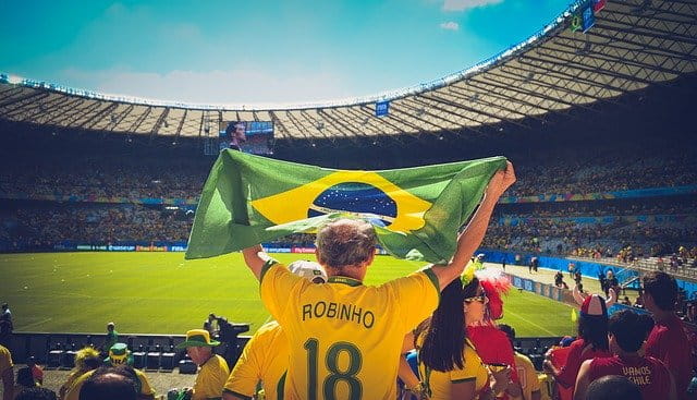 Un aficionado levanta la bandera de Brasil durante un partido de fútbol.