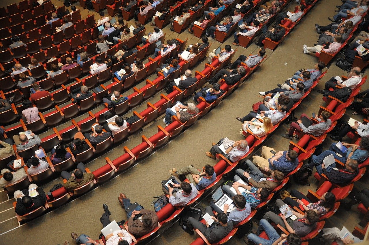 Grupo de gente sentada en un auditorio.