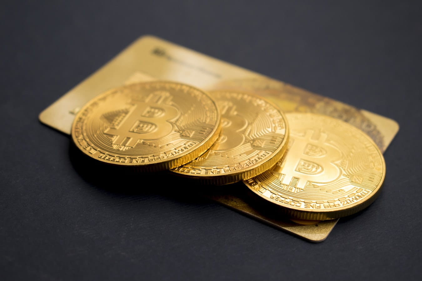 Tres monedas de Bitcoin sobre una tarjeta de crédito.