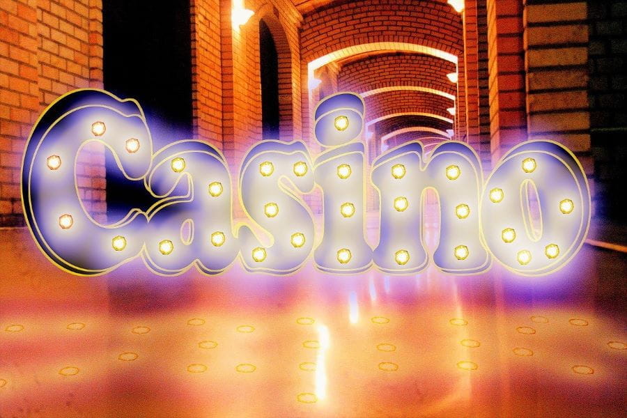 La palabra CASINO aparece iluminada sobre el fondo de un salón.