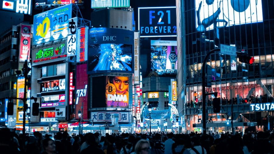 Carteles luminosos publicitarios en una ciudad de noche.