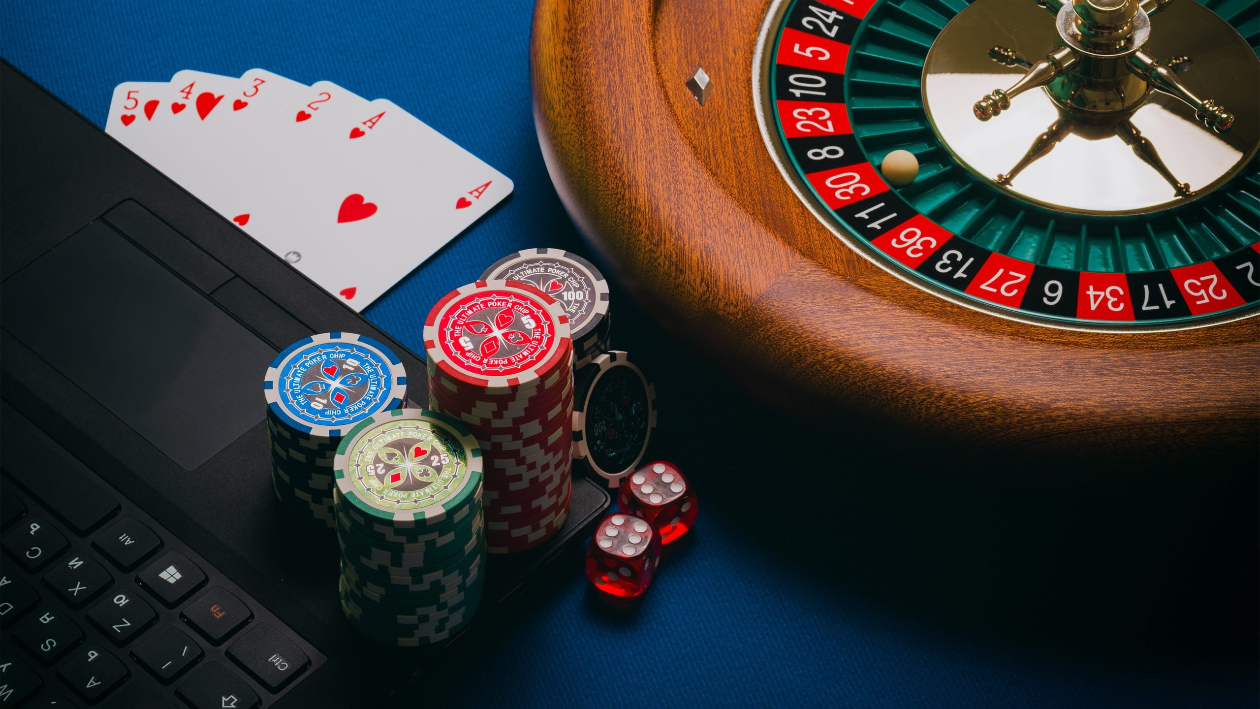 Cilindro y fichas de la ruleta cerca de un ordenador portatil.