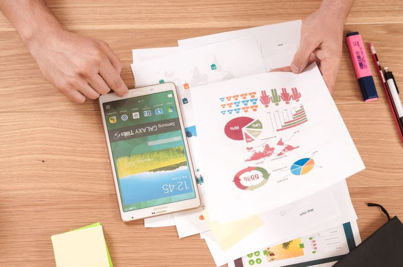 Smartphone y hojas con gráficos sobre una mesa.