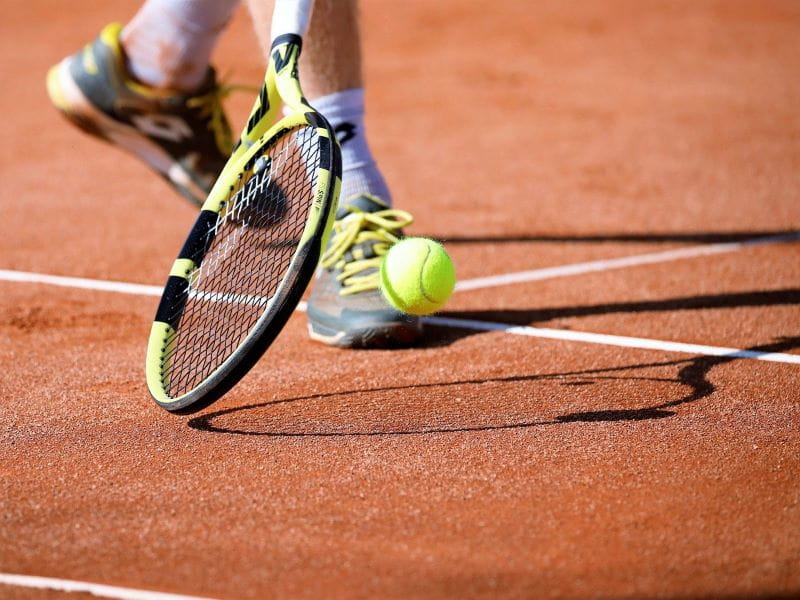 Raqueta de tenis y pelota en una pista.