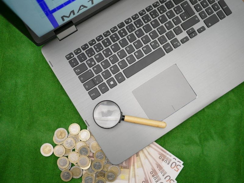Ordenador personal con lupa y monedas y billetes de euro.