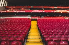 Gradas vacías en un estadio con diversos carteles publicitarios.