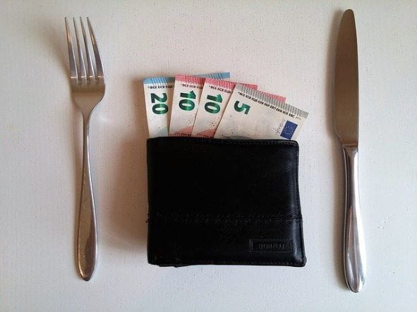 Cartera con billetes de euro entre un cuchillo y un tenedor.
