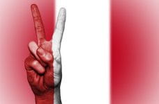 Signo de la victoria sobre la bandera del Perú.