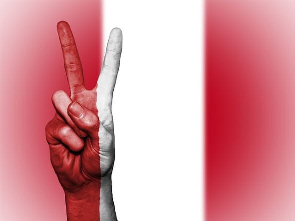 Signo de la victoria sobre la bandera del Perú.