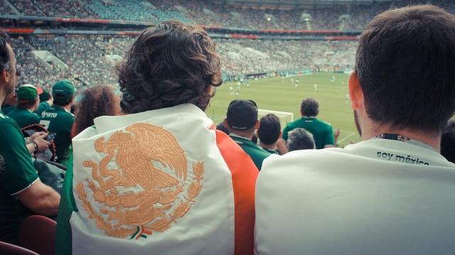 Aficionado al fútbol envuelto en una bandera mexicana.