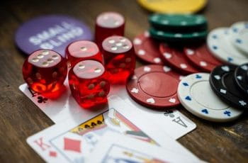 Dados, fichas y cartas de póker esparcidos sobre una mesa.