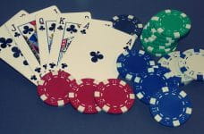 Cinco cartas de poker formando escalera real junto con fichas de casino.