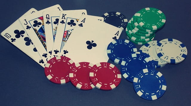 Cinco cartas de poker formando escalera real junto con fichas de casino.