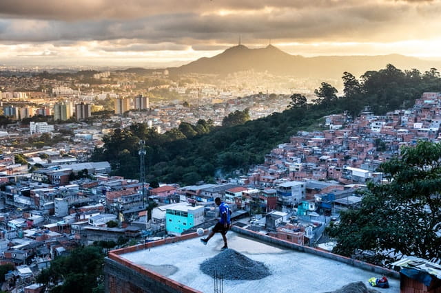 Chutando un balón de fútbol encima de un tejado en una favela en Brasil.
