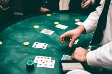 Mano de crupier de casino jugando en la mesa con cartas de póker.