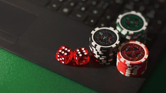 Fichas de póker y dados sobre un ordenador portátil.