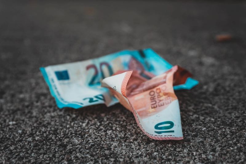 Dos billetes de 10 y 20 euros arrugados en el suelo.
