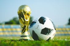 Copa del Mundo de fútbol y balón sobre el césped.