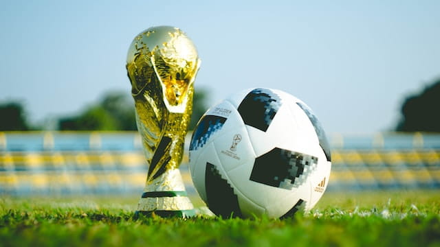 Copa del Mundo de fútbol y balón sobre el césped.