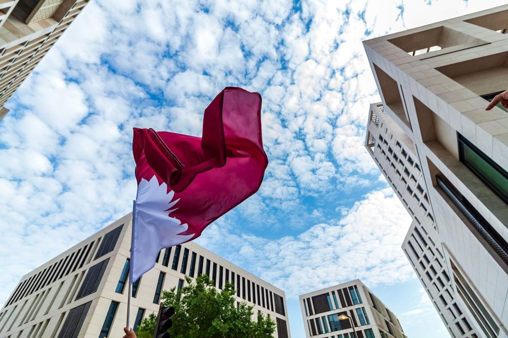 Bandera de Catar y edificios en la ciudad de Doha.