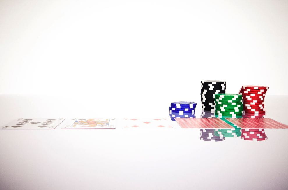 Fichas y cartas de póker sobre una superficie transparente.