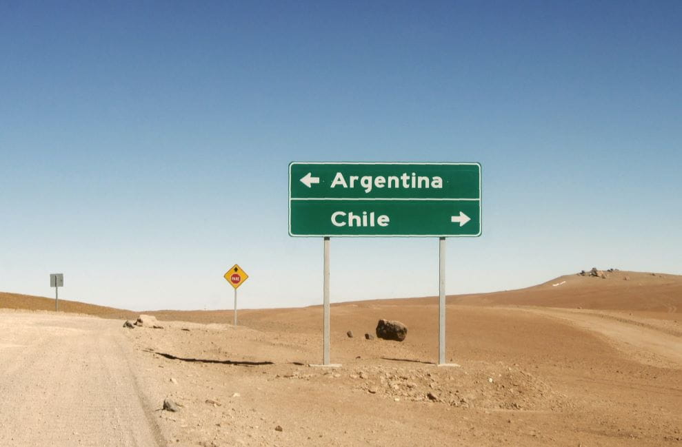 Carretera en el desierto con una señal con dos direcciones: a Chile y a Argentina.