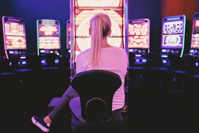 Mujer sentada delante de una máquina tragaperras.