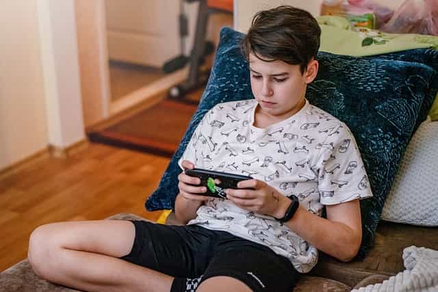 Un chico menor de edad juega con su teléfono móvil.