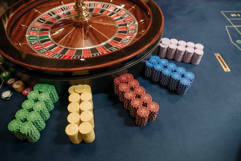Ruleta de casino con varios montones de fichas, de diferentes colores, alrededor.