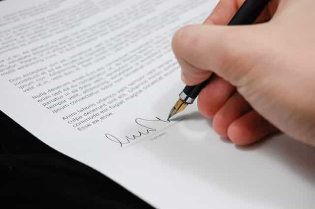 Persona firmando con pluma un documento legal.