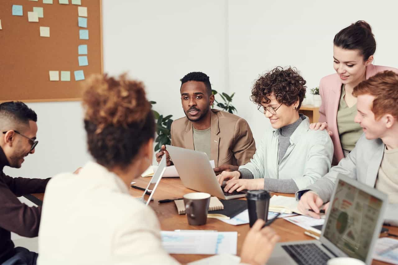 Grupo de empleados de diferentes etnias en una sala de reuniones.