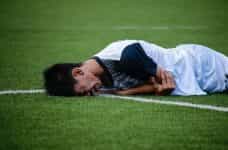 Futbolista tumbado en el campo con gesto de dolor.