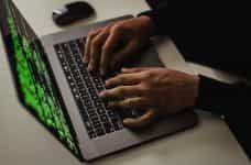 Manos de un hombre sobre el teclado de un ordenador portatil.