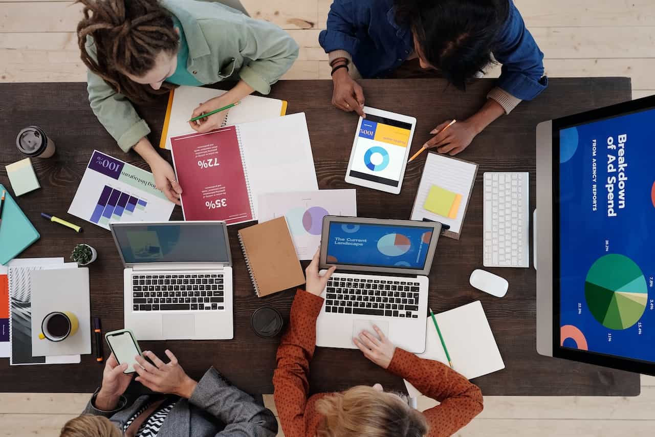 Grupo de personas en una mesa de trabajo con informes y portátiles.