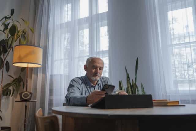 Adulto mayor introduciendo los datos de su tarjeta en el móvil.