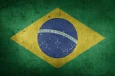 Chica brasileña pasando por delante de una pared pintada como la bandera de Brasil.