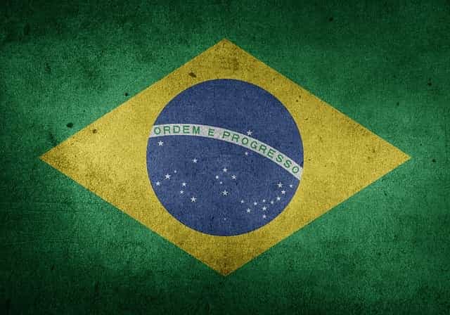 Chica brasileña pasando por delante de una pared pintada como la bandera de Brasil.