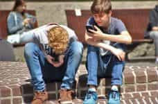 Dos chicos jóvenes en la calle usando sus teléfonos inteligentes.