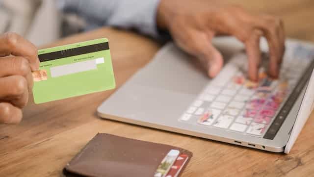 Hombre introduciendo los datos de su tarjeta bancaria en su ordenador.