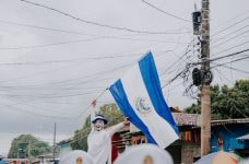 Persona disfrazada ondeando la bandera de El Salvador.