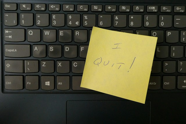 Teclado de un ordenador con un post-it encima en el que se lee I quit, dimito.