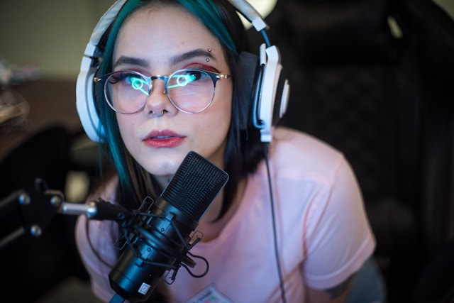 Chica streamer delante de un micrófono frente a su ordenador.