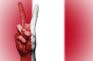 Mano con dos dedos levantados en símbolo de victoria sobre una bandera de Perú.